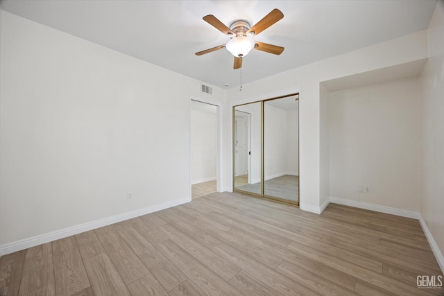 unfurnished bedroom featuring light wood finished floors, baseboards, visible vents, and two closets