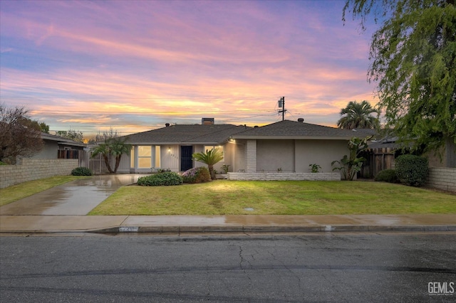 single story home with stucco siding, fence, concrete driveway, and a yard