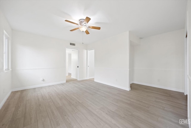 spare room with a ceiling fan, light wood-type flooring, visible vents, and baseboards