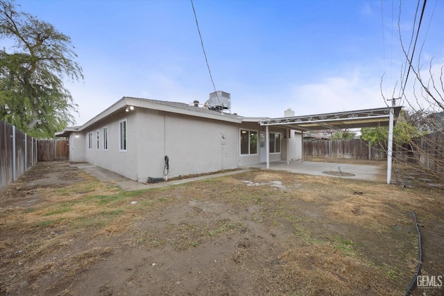 rear view of house with a fenced backyard, a patio, and stucco siding