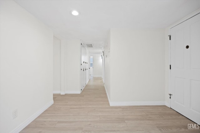 hallway with baseboards, recessed lighting, and light wood-style floors