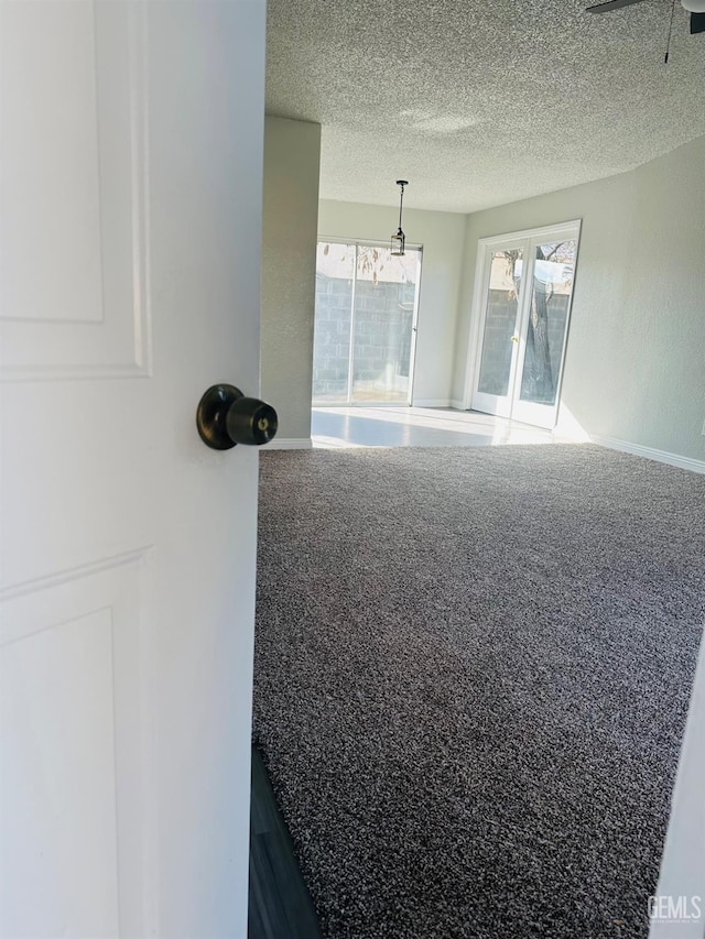 spare room with carpet, a textured ceiling, and french doors