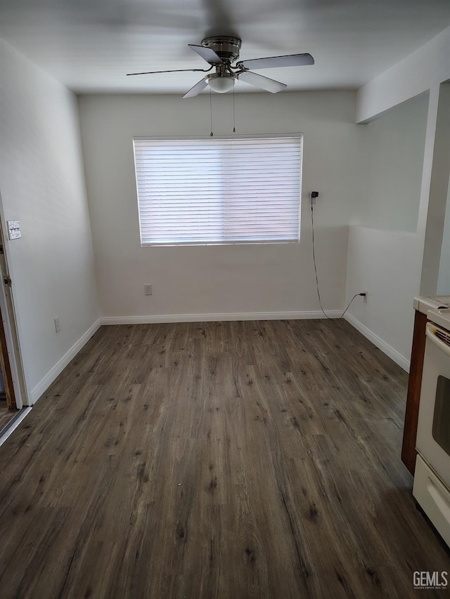 spare room with baseboards, dark wood finished floors, and a ceiling fan