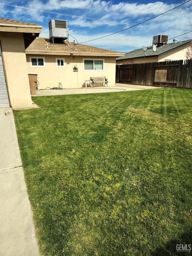 view of yard with a patio area, fence, and central AC unit