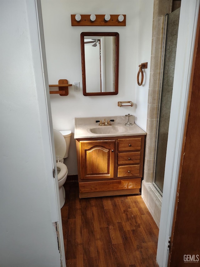 full bath with an enclosed shower, vanity, toilet, and wood finished floors