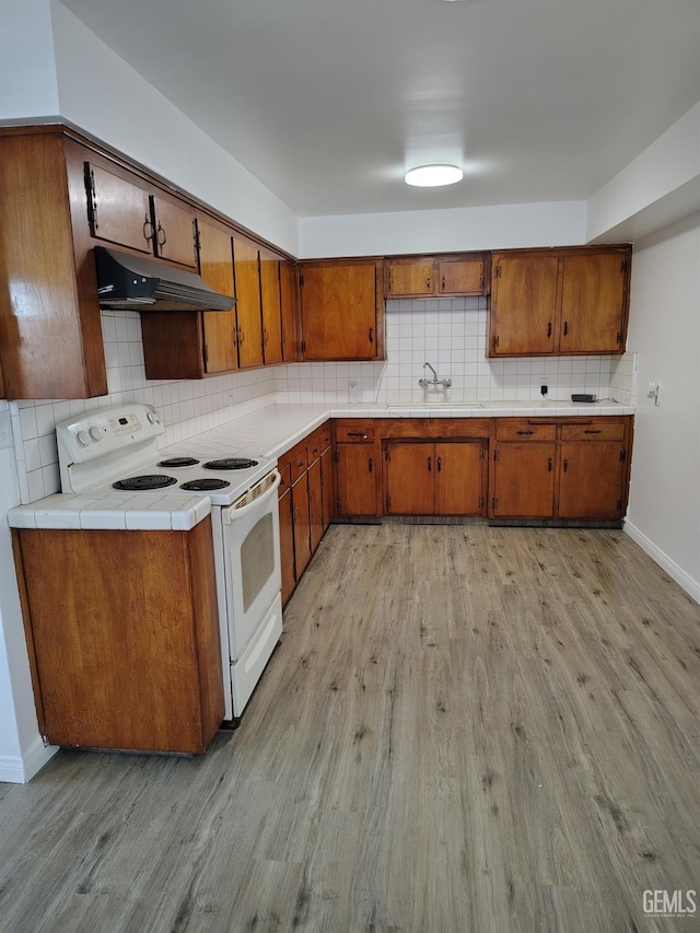 kitchen featuring white range with electric cooktop, brown cabinets, light wood-type flooring, under cabinet range hood, and a sink