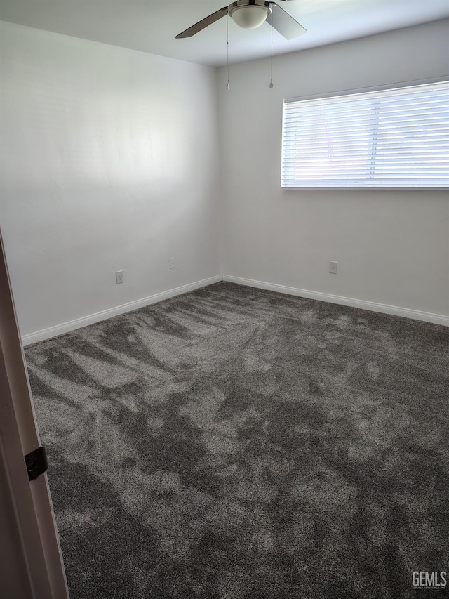 carpeted spare room with ceiling fan and baseboards