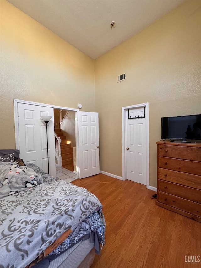 bedroom with high vaulted ceiling and light hardwood / wood-style floors