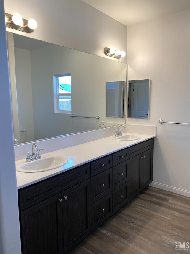 bathroom with toilet, vanity, and wood-type flooring