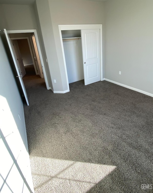 unfurnished bedroom featuring a closet and dark colored carpet