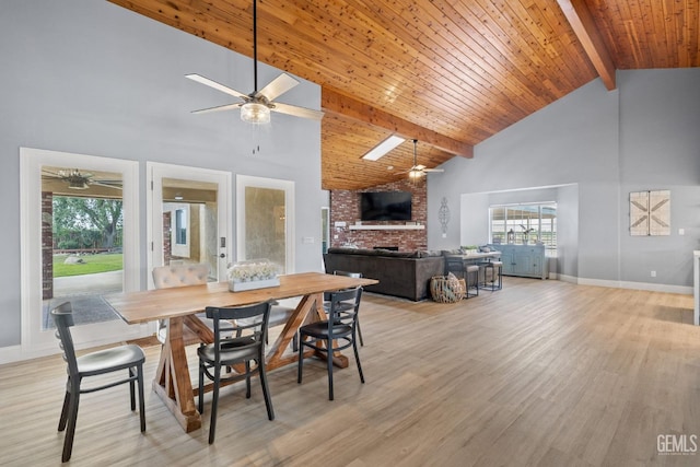 dining room featuring beamed ceiling, wooden ceiling, a brick fireplace, high vaulted ceiling, and light hardwood / wood-style flooring