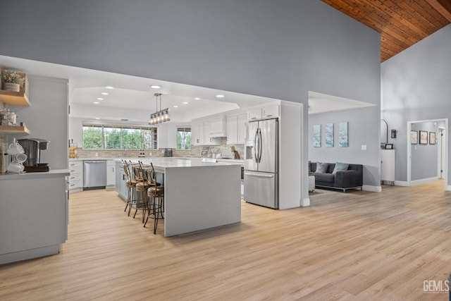 kitchen featuring a kitchen bar, white cabinets, a kitchen island, backsplash, and stainless steel appliances