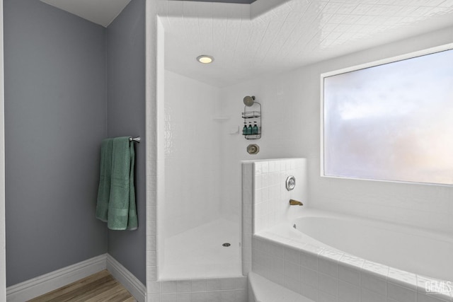 bathroom featuring hardwood / wood-style flooring and a relaxing tiled tub