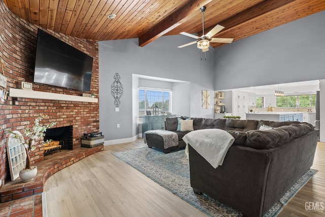 living room with wood ceiling, vaulted ceiling with beams, a fireplace, light wood-type flooring, and ceiling fan