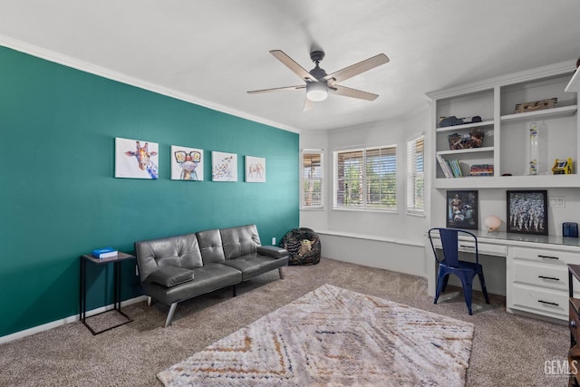 carpeted home office featuring built in desk, ceiling fan, and crown molding