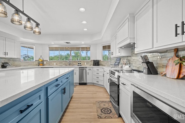 kitchen featuring decorative light fixtures, blue cabinetry, white cabinets, and stainless steel electric range