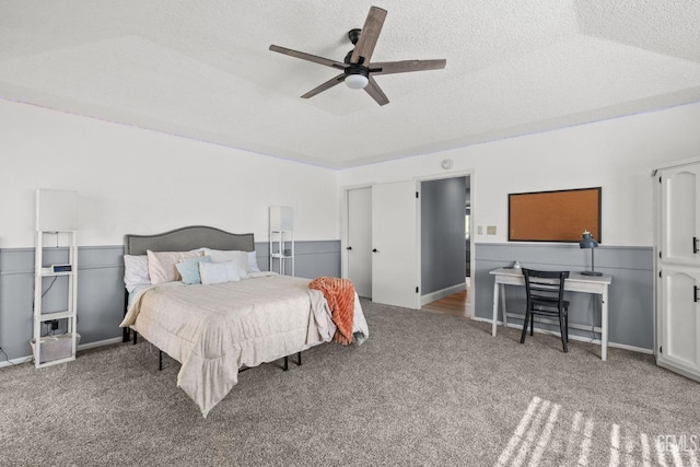 bedroom with ceiling fan, carpet, and a textured ceiling