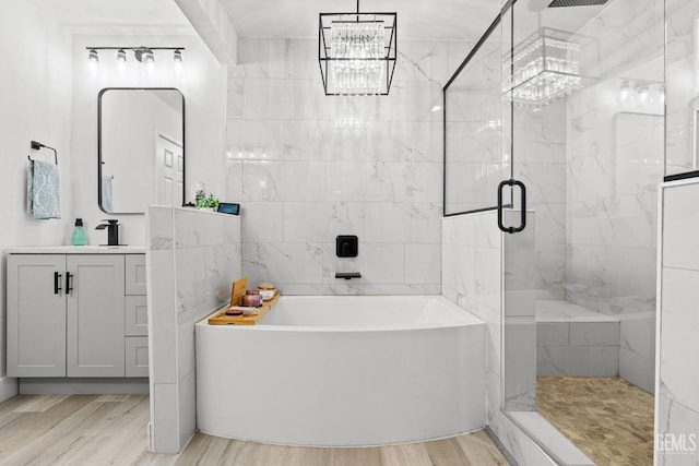 bathroom featuring a notable chandelier, hardwood / wood-style floors, separate shower and tub, and vanity