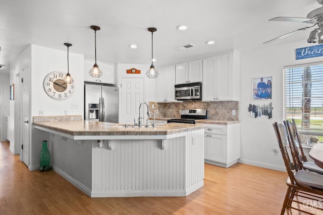 kitchen featuring white cabinetry, appliances with stainless steel finishes, and a breakfast bar