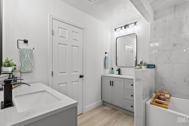 bathroom featuring vanity, a tub, and wood-type flooring