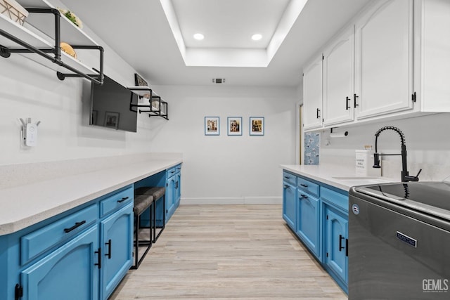 kitchen with sink, blue cabinetry, white cabinets, a tray ceiling, and range