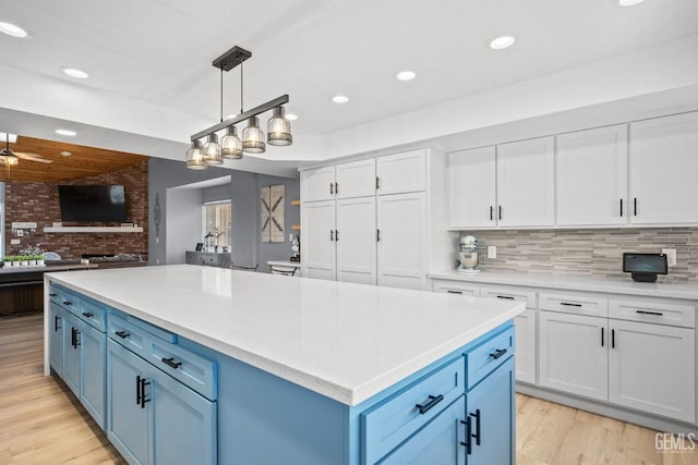 kitchen featuring ceiling fan, hanging light fixtures, white cabinets, blue cabinets, and decorative backsplash