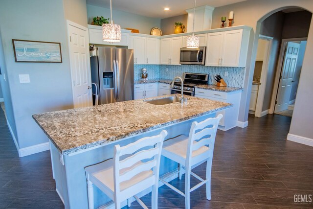 1850 Verdugo Ln, Bakersfield, CA 93312 - kitchen featuring stainless steel appliances, arched walkways, white cabinetry, a center island with sink, and tasteful backsplash
