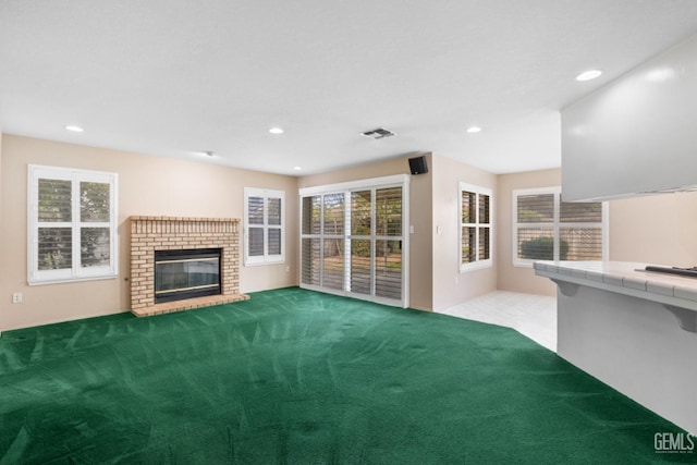 unfurnished living room featuring carpet, a brick fireplace, recessed lighting, and visible vents