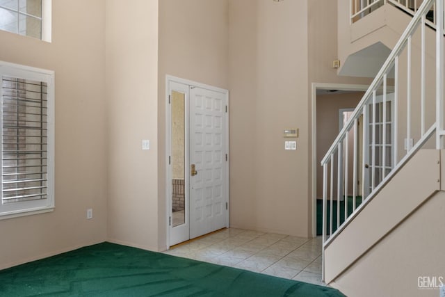 entrance foyer featuring tile patterned floors, stairway, and a towering ceiling