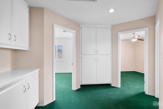 hallway featuring dark carpet and baseboards