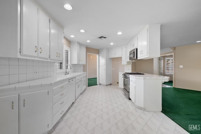 kitchen featuring visible vents, a sink, stainless steel appliances, and tile counters