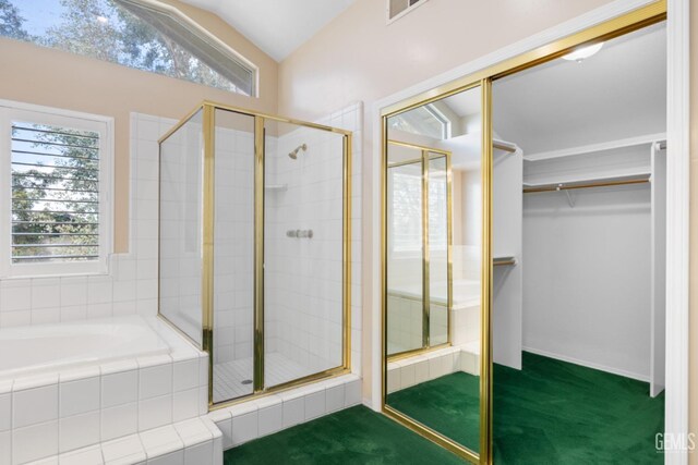 bathroom featuring a spacious closet, visible vents, a garden tub, vaulted ceiling, and a stall shower