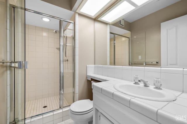 bathroom featuring tasteful backsplash, toilet, vanity, and a shower stall