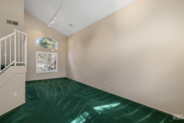 carpeted empty room featuring rail lighting, visible vents, and high vaulted ceiling