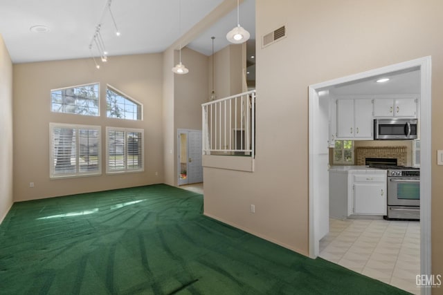 unfurnished living room featuring track lighting, visible vents, and high vaulted ceiling