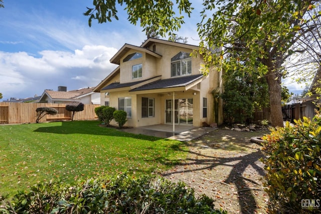 rear view of house with a patio area, a fenced backyard, stucco siding, and a yard