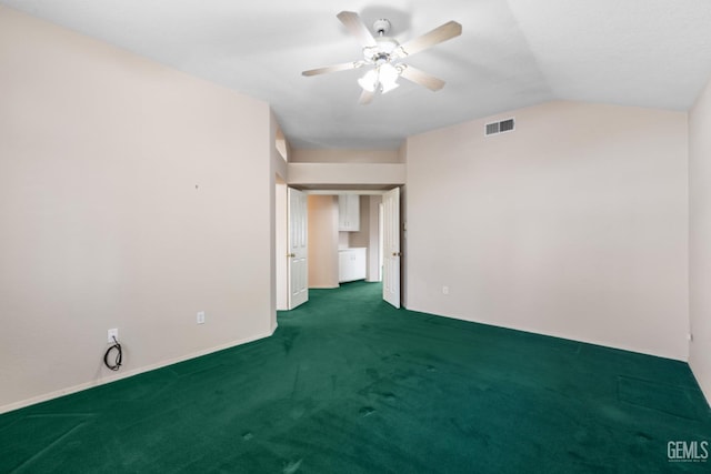 spare room featuring vaulted ceiling, visible vents, ceiling fan, and dark colored carpet