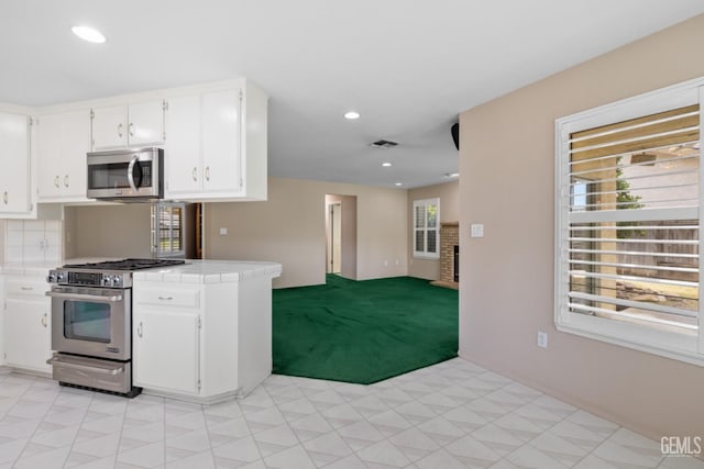 kitchen with tile countertops, visible vents, plenty of natural light, and appliances with stainless steel finishes