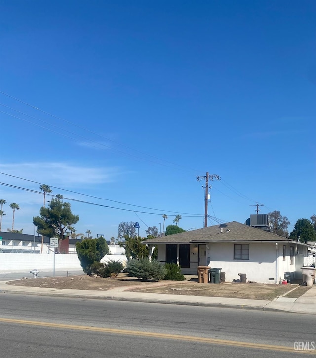 single story home with stucco siding, central AC unit, and fence