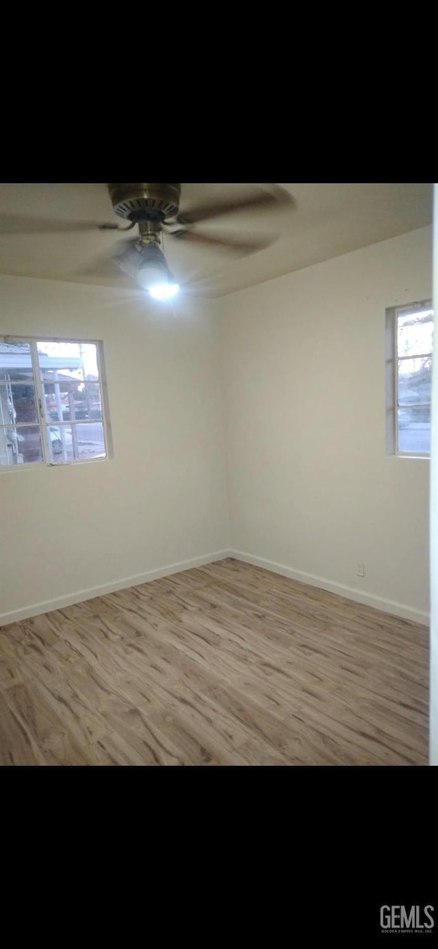 unfurnished room featuring light wood finished floors, baseboards, and a ceiling fan