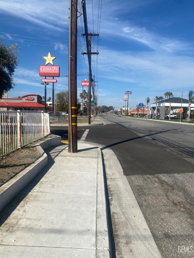 view of road featuring street lights, curbs, and sidewalks