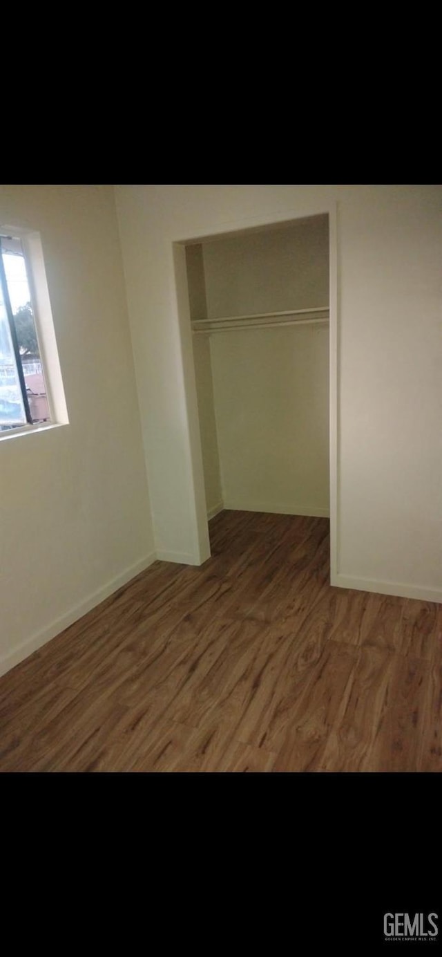 unfurnished bedroom featuring a closet, dark wood finished floors, and baseboards