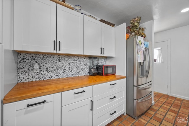 kitchen with white cabinetry, decorative backsplash, and stainless steel fridge