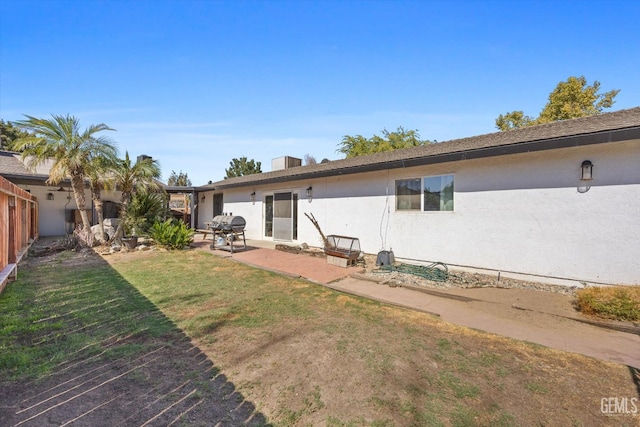 back of house with a lawn and a patio