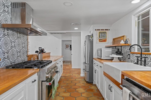 kitchen featuring white cabinetry, sink, wall chimney exhaust hood, tasteful backsplash, and appliances with stainless steel finishes