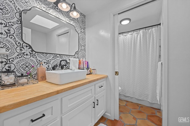 bathroom featuring backsplash, a skylight, tile patterned floors, vanity, and toilet