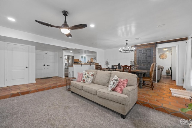 tiled living room with ceiling fan with notable chandelier and a barn door