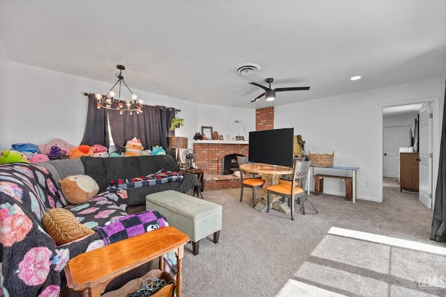 carpeted living room with ceiling fan with notable chandelier and a brick fireplace