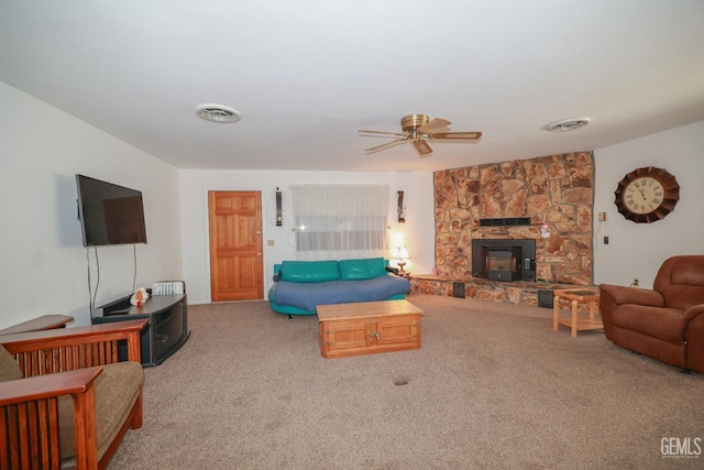 living area featuring visible vents, a ceiling fan, carpet, and a stone fireplace