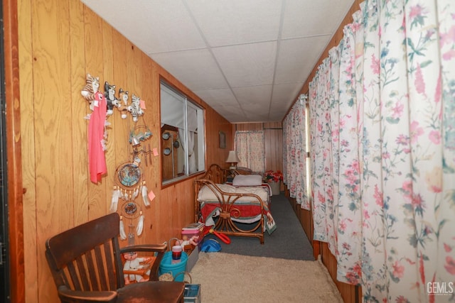 bedroom featuring carpet flooring, wood walls, and a paneled ceiling